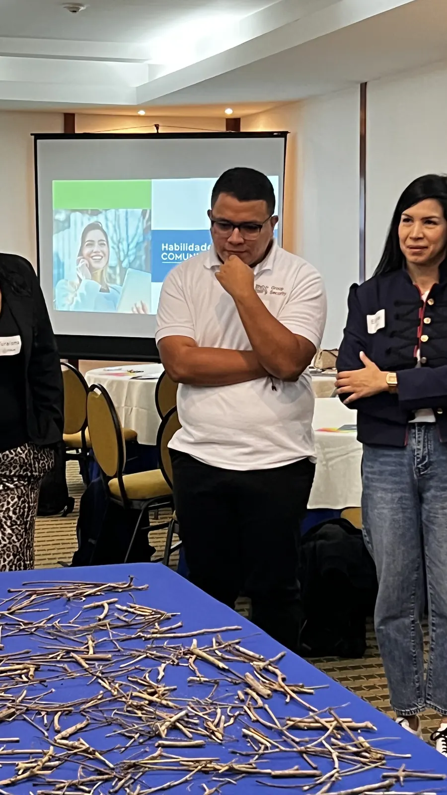 Participantes de pie alrededor de una mesa con ramas durante un ejercicio vivencial del taller de Forja